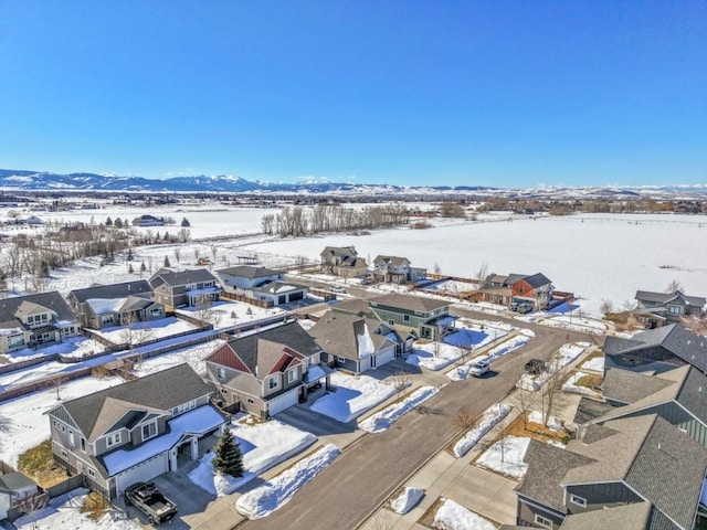 snowy aerial view with a mountain view and a residential view