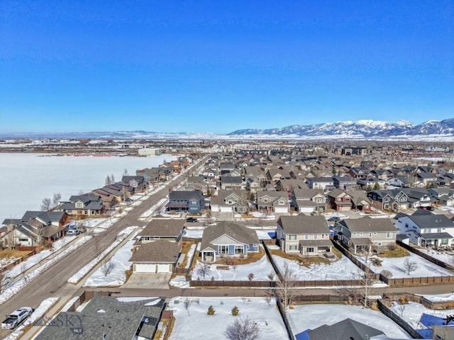 snowy aerial view featuring a mountain view and a residential view