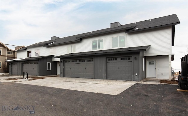 view of property featuring board and batten siding, driveway, and a garage