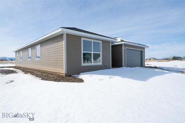 snow covered property with an outbuilding and a garage