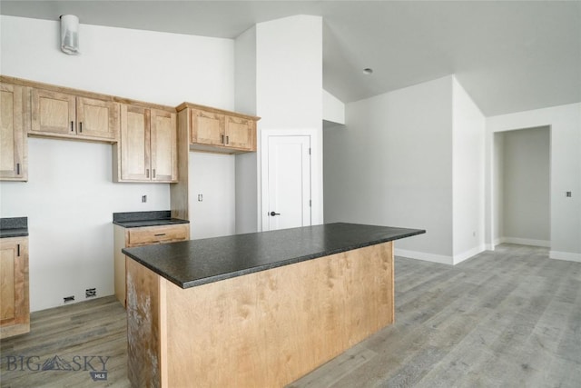 kitchen featuring dark countertops, light wood-style floors, baseboards, and a center island