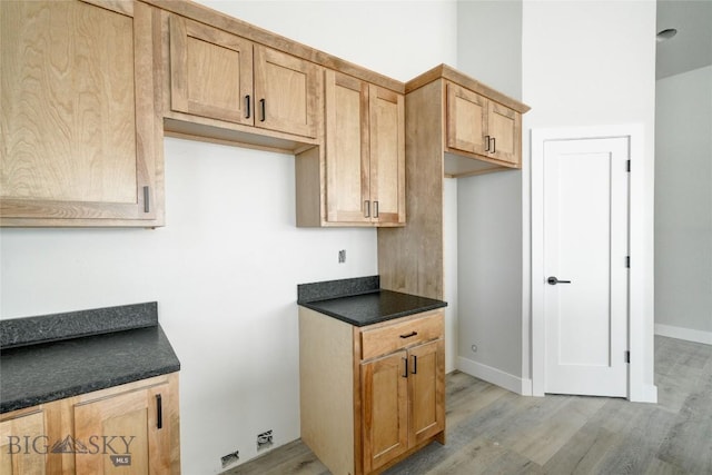 kitchen featuring light wood-type flooring, baseboards, and dark countertops