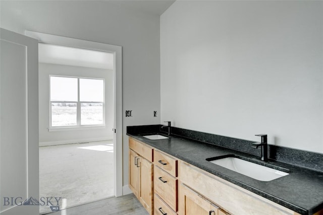 full bath featuring double vanity, baseboards, and a sink