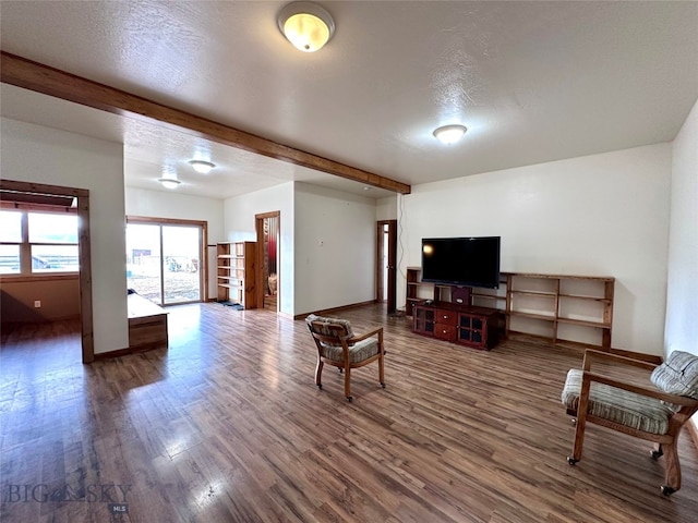 living room with beam ceiling, wood finished floors, baseboards, and a textured ceiling