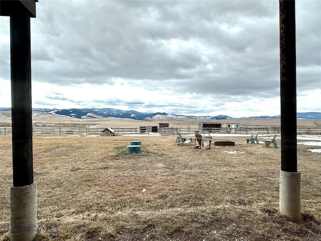 view of yard with an outdoor structure, fence, a rural view, and a mountain view