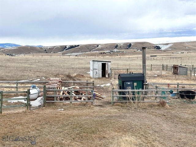 view of outbuilding with a mountain view, a rural view, an outdoor structure, and fence