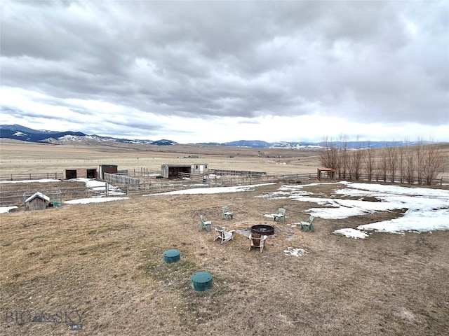 view of yard featuring a mountain view, a rural view, an outdoor fire pit, and fence