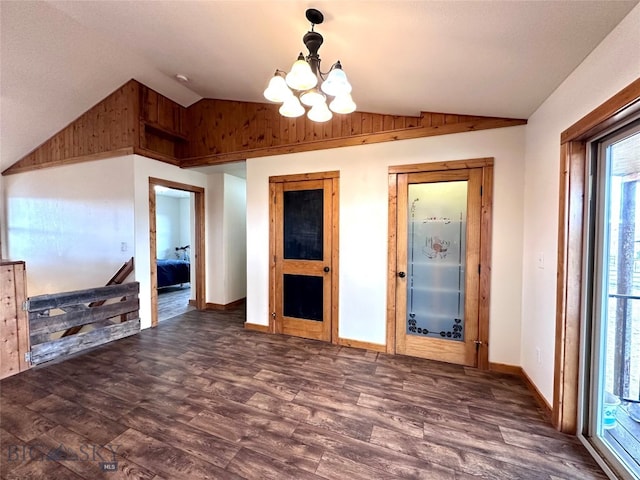 unfurnished room featuring baseboards, an inviting chandelier, wood finished floors, and vaulted ceiling