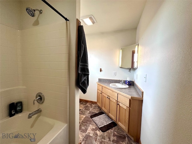 full bath with shower / bathing tub combination, baseboards, vanity, and stone finish flooring