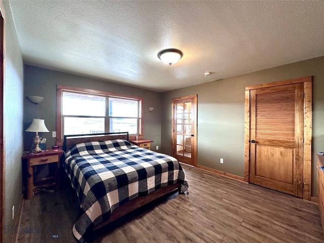 bedroom with a textured ceiling, baseboards, and wood finished floors