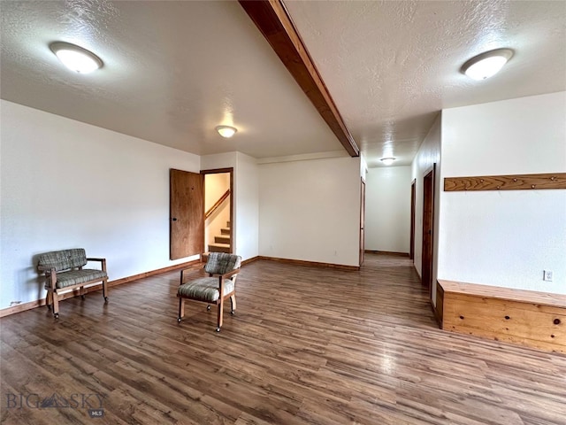 unfurnished room with beam ceiling, a textured ceiling, baseboards, and wood finished floors