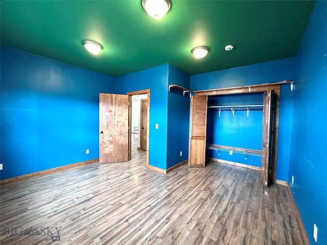 unfurnished bedroom featuring a closet, baseboards, and wood finished floors