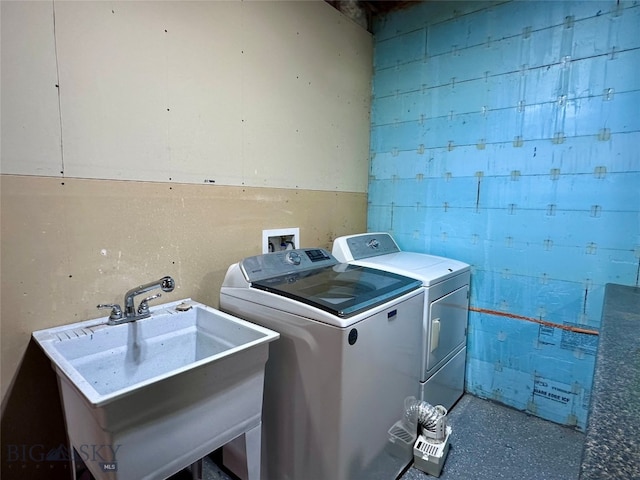 laundry room with laundry area, concrete block wall, independent washer and dryer, and a sink