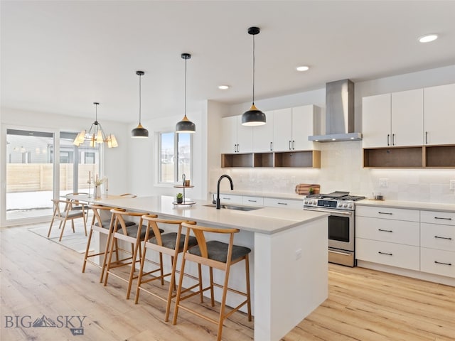 2824 S 30th Ave, Bozeman, MT 59718 - kitchen featuring a sink, wall chimney range hood, gas stove, decorative backsplash, and a breakfast bar area