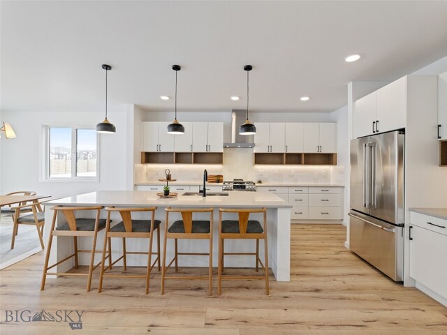 2824 S 30th Ave, Bozeman, MT 59718 - kitchen featuring high quality fridge, wall chimney exhaust hood, a sink, light wood-style flooring, and a kitchen bar