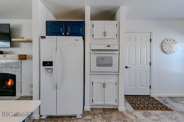 kitchen featuring light countertops, a fireplace, white appliances, white cabinetry, and blue cabinets