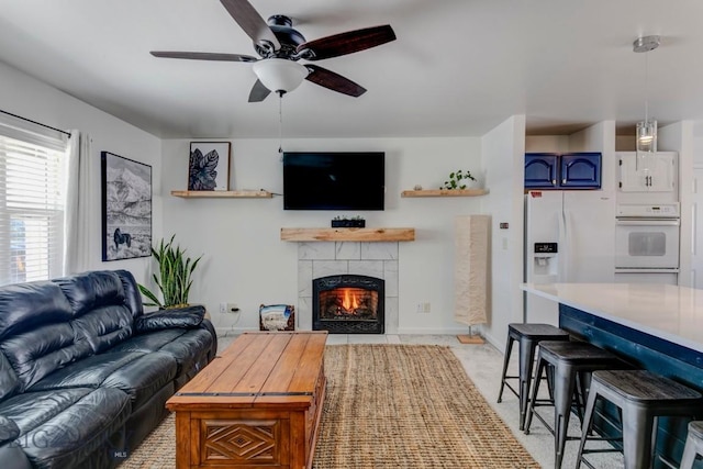 living room featuring a tiled fireplace, baseboards, and ceiling fan