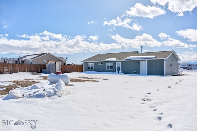 snow covered back of property with fence