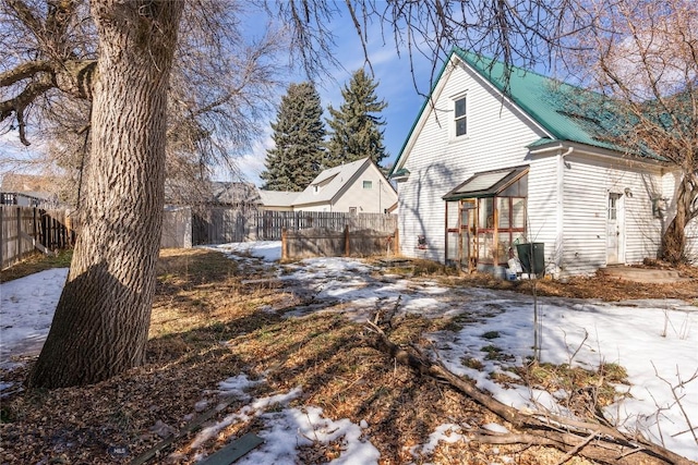 snow covered house with a fenced backyard and metal roof