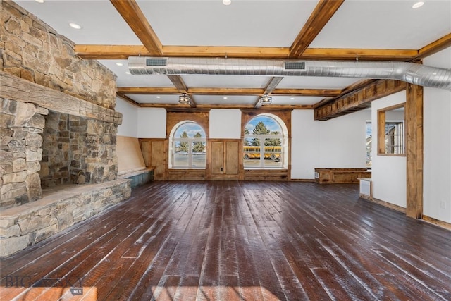 unfurnished living room with beamed ceiling, wood-type flooring, a stone fireplace, and visible vents