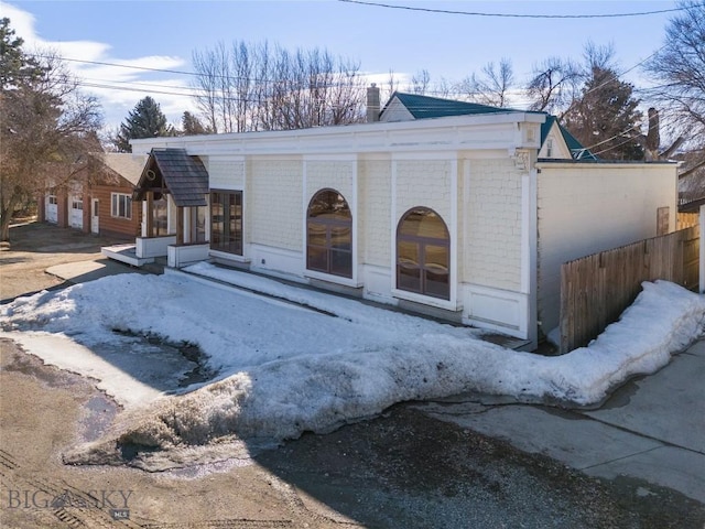 view of front of home with french doors, brick siding, and a chimney