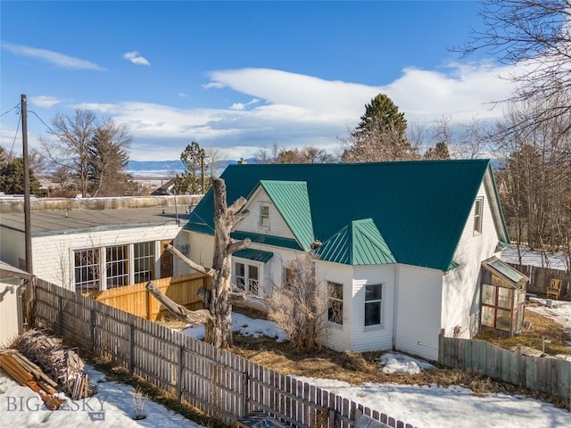 exterior space featuring a standing seam roof, metal roof, fence, and a chimney