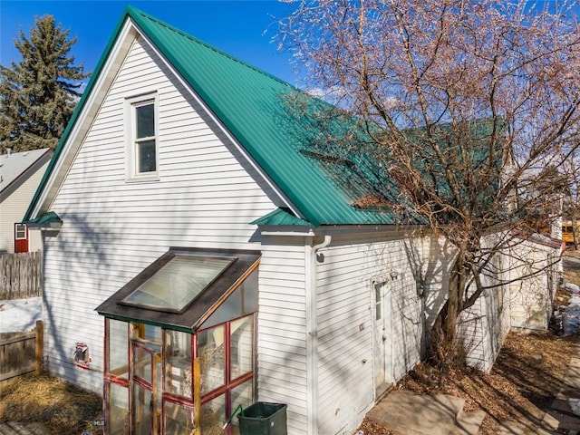 back of house featuring fence and metal roof