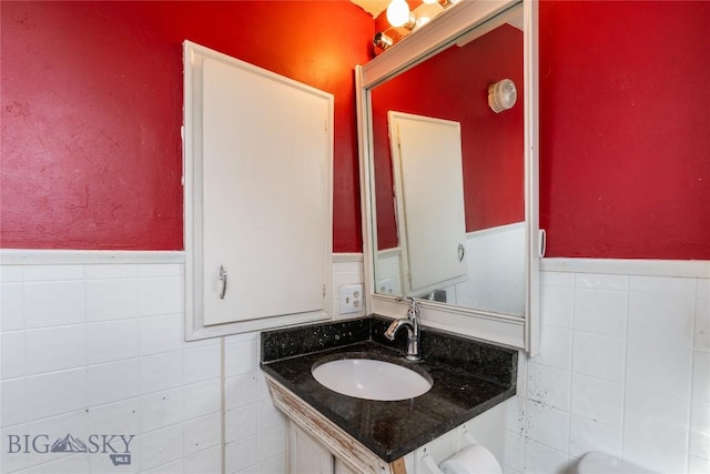 bathroom with vanity, tile walls, and a wainscoted wall