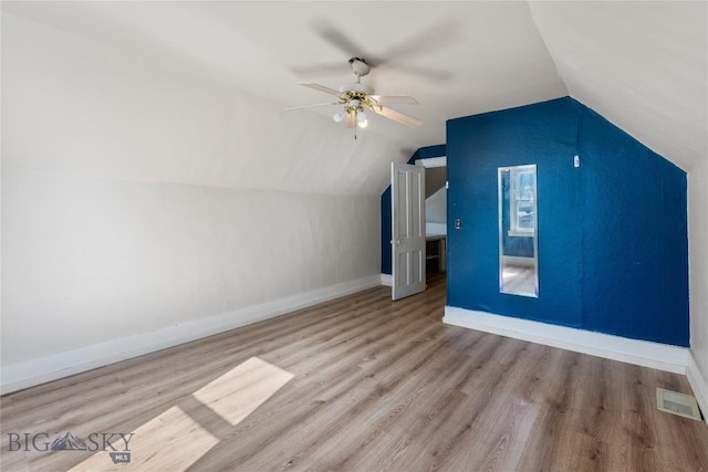 additional living space with vaulted ceiling, visible vents, baseboards, and wood finished floors