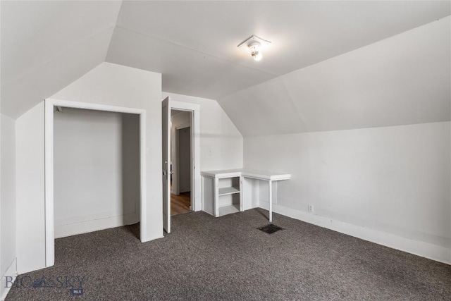 additional living space featuring dark colored carpet and vaulted ceiling