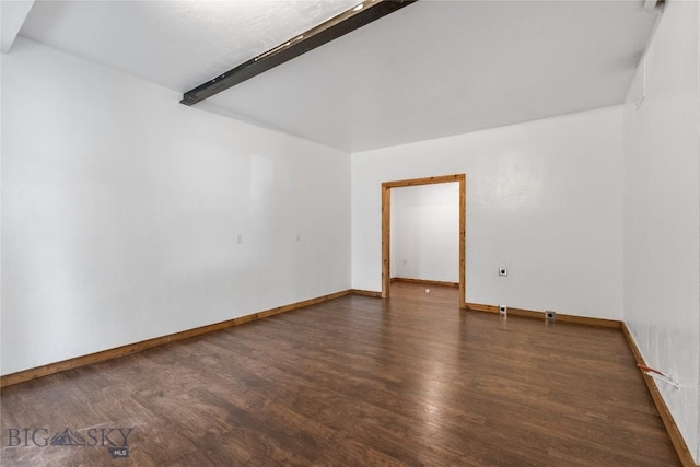 spare room with beam ceiling, baseboards, and wood finished floors