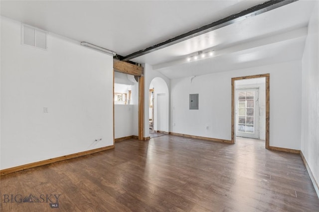 empty room featuring visible vents, beamed ceiling, electric panel, wood finished floors, and arched walkways