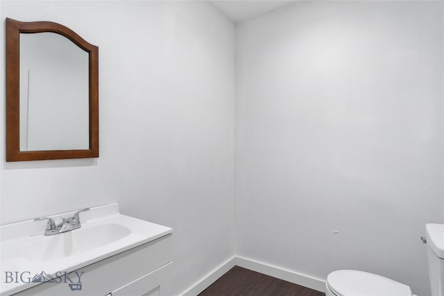 half bathroom featuring baseboards, toilet, wood finished floors, and vanity