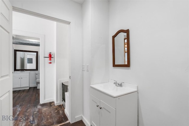 bathroom featuring baseboards, toilet, wood finished floors, and vanity