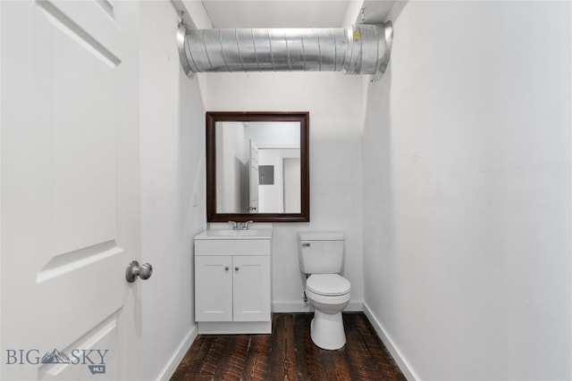 half bath with baseboards, toilet, wood finished floors, and vanity