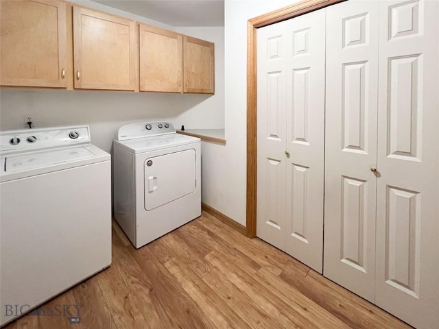 laundry room featuring washing machine and dryer, cabinet space, and light wood-type flooring