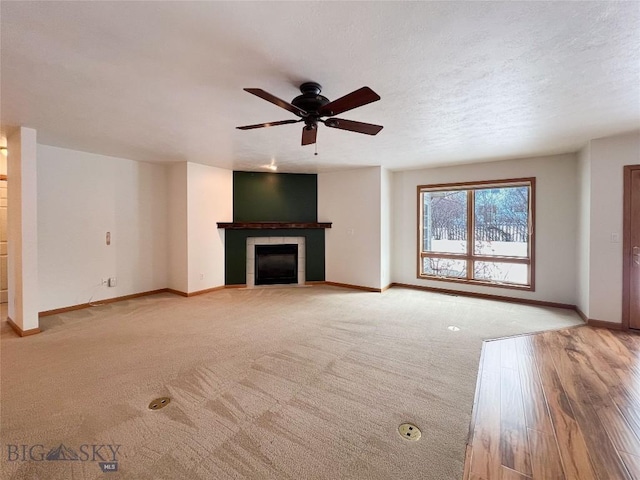 unfurnished living room with ceiling fan, a fireplace, a textured ceiling, and baseboards