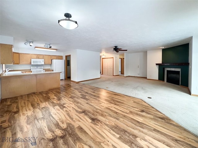 unfurnished living room featuring light wood-type flooring, a sink, a fireplace, baseboards, and ceiling fan