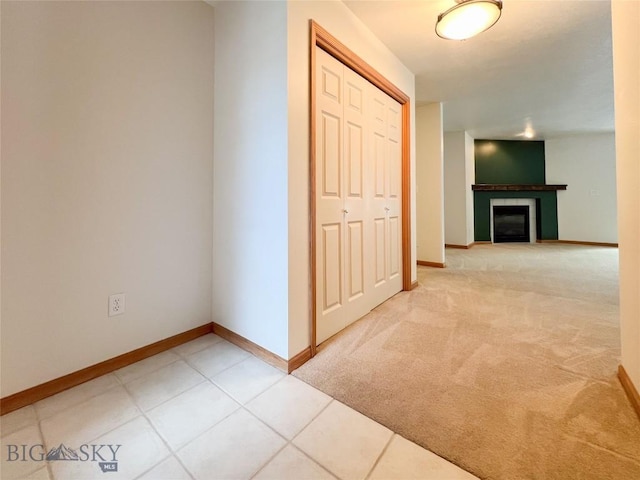 hall with light carpet, light tile patterned floors, and baseboards