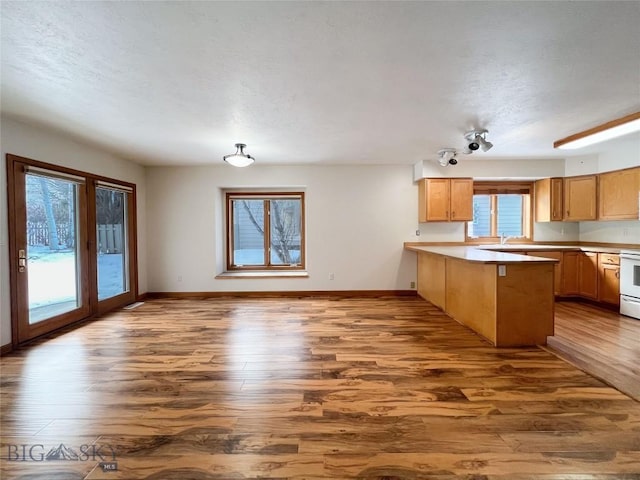 kitchen with baseboards, dark wood-type flooring, a peninsula, and white electric range oven