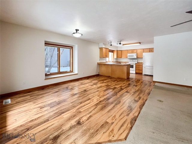 kitchen with visible vents, wood finished floors, open floor plan, white appliances, and a peninsula