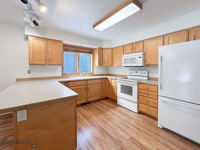 kitchen with white appliances, a peninsula, light wood-style flooring, a sink, and light countertops