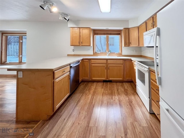 kitchen featuring white appliances, a peninsula, light wood-style floors, and a wealth of natural light