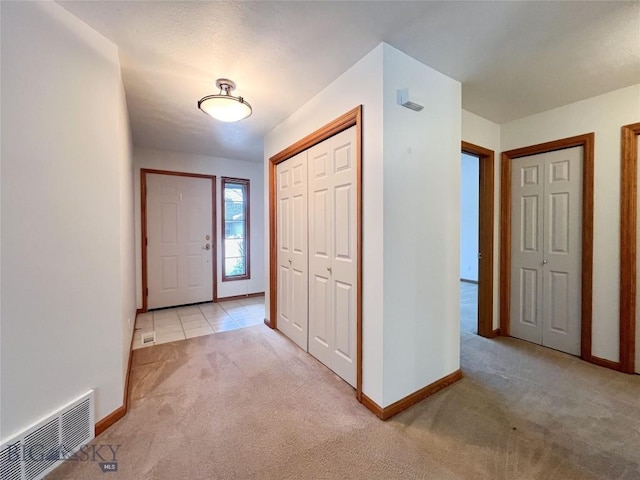 entrance foyer featuring visible vents, baseboards, and light colored carpet