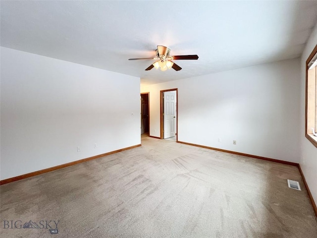 empty room featuring visible vents, light colored carpet, baseboards, and ceiling fan