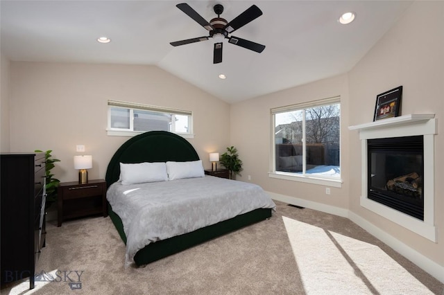 bedroom with visible vents, baseboards, vaulted ceiling, light carpet, and a glass covered fireplace