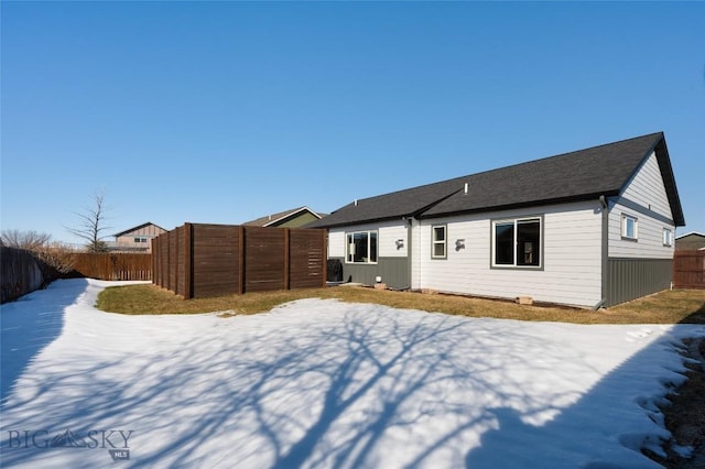 snow covered house with a fenced backyard