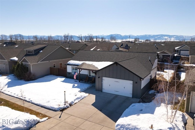 snowy aerial view featuring a mountain view and a residential view