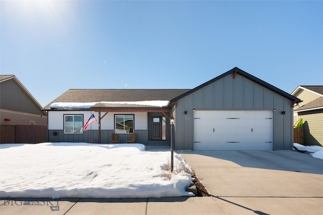 view of front facade featuring board and batten siding, concrete driveway, an attached garage, and fence