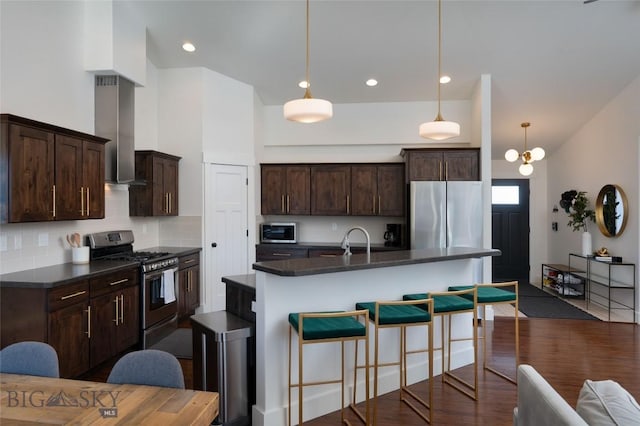 kitchen featuring dark countertops, a breakfast bar area, a high ceiling, dark wood-style floors, and stainless steel appliances